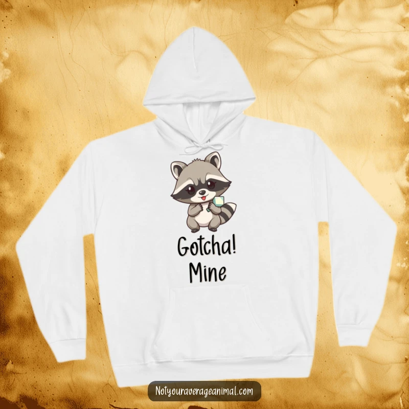 Funny hoodie featuring a cheeky raccoon character with a glint in its eye, proudly displaying a stolen shiny object.